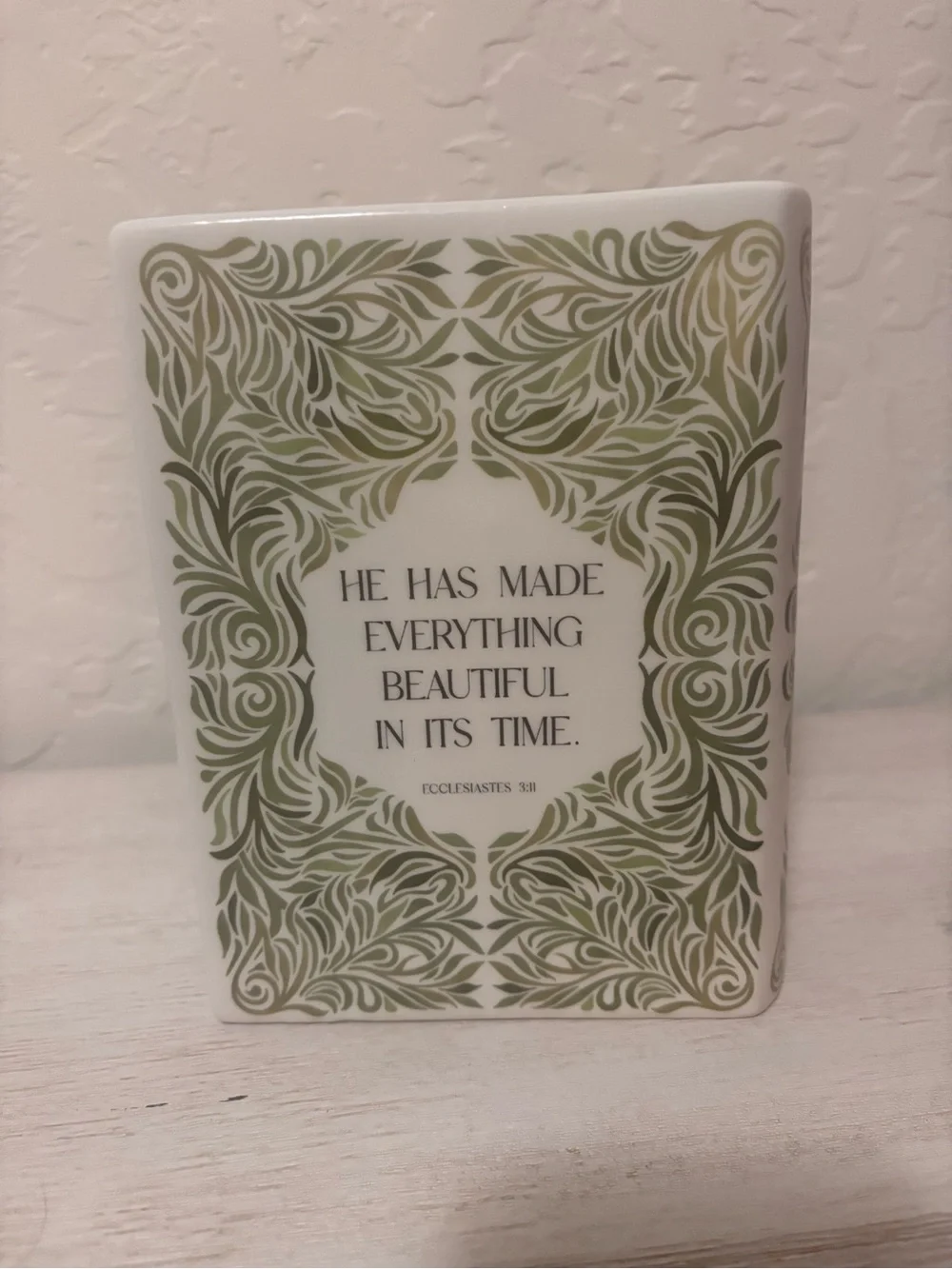 ceramic book vase with green floral swirls and the words…
